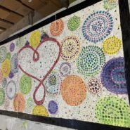 a colorful mosaic work with a bunch of circles in various sizes with a heart in the middle