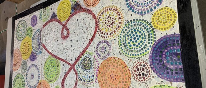 a colorful mosaic work with a bunch of circles in various sizes with a heart in the middle